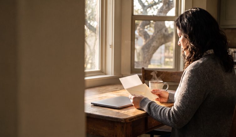 A woman at her kitchen table in a Central Texas home reads a letter about her stalled divorce case