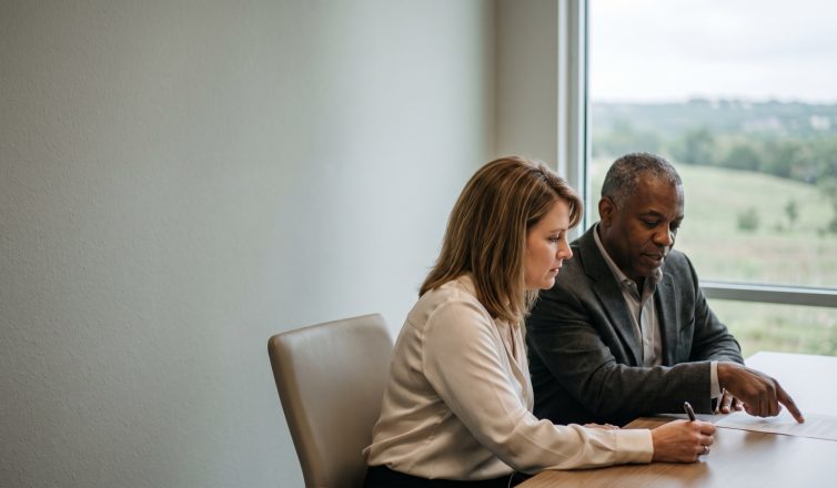 Attorney pointing to a term in a mediated settlement agreement while his client reads it before signing